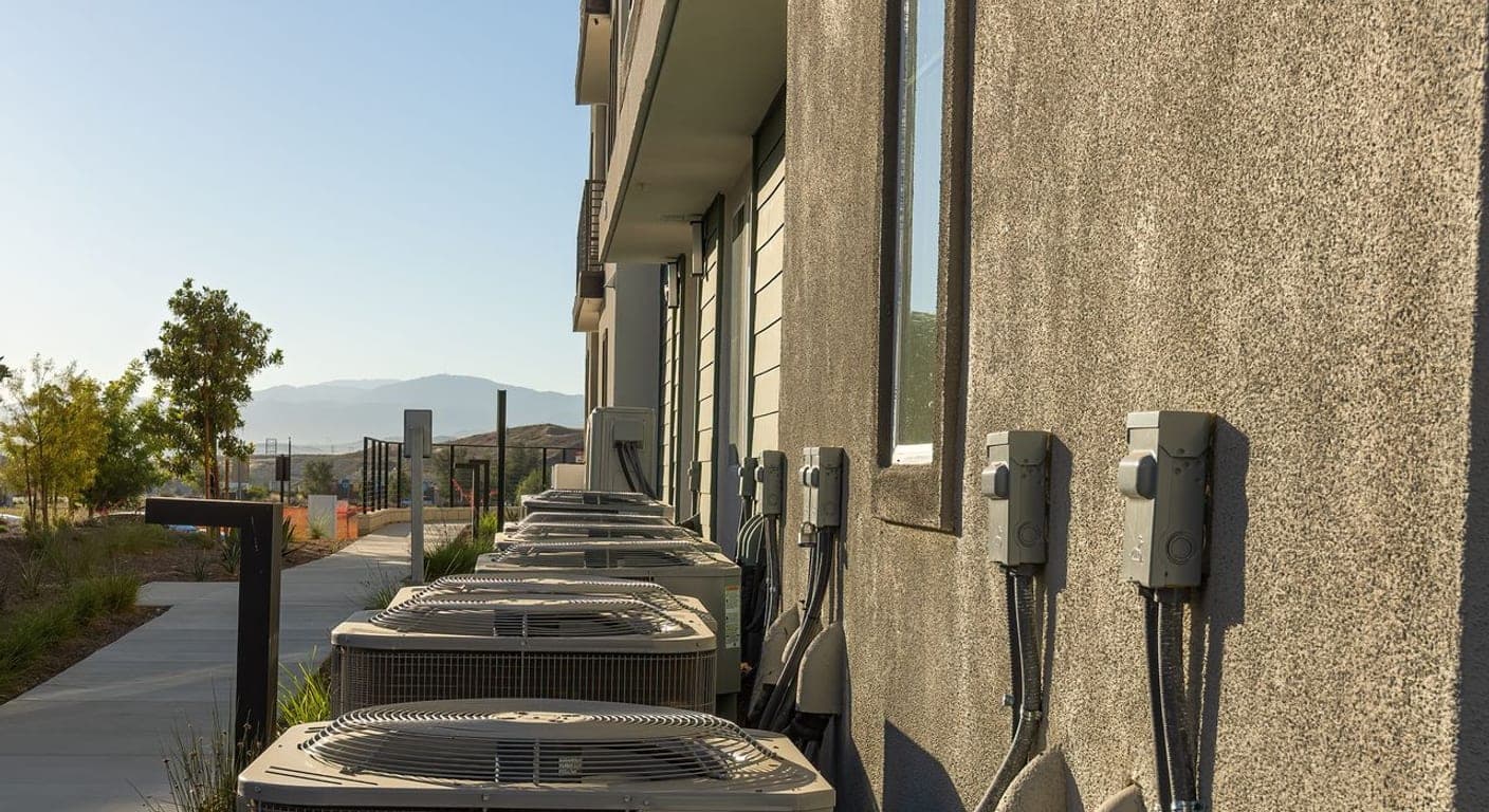 Row of AC condenser units installed along a building